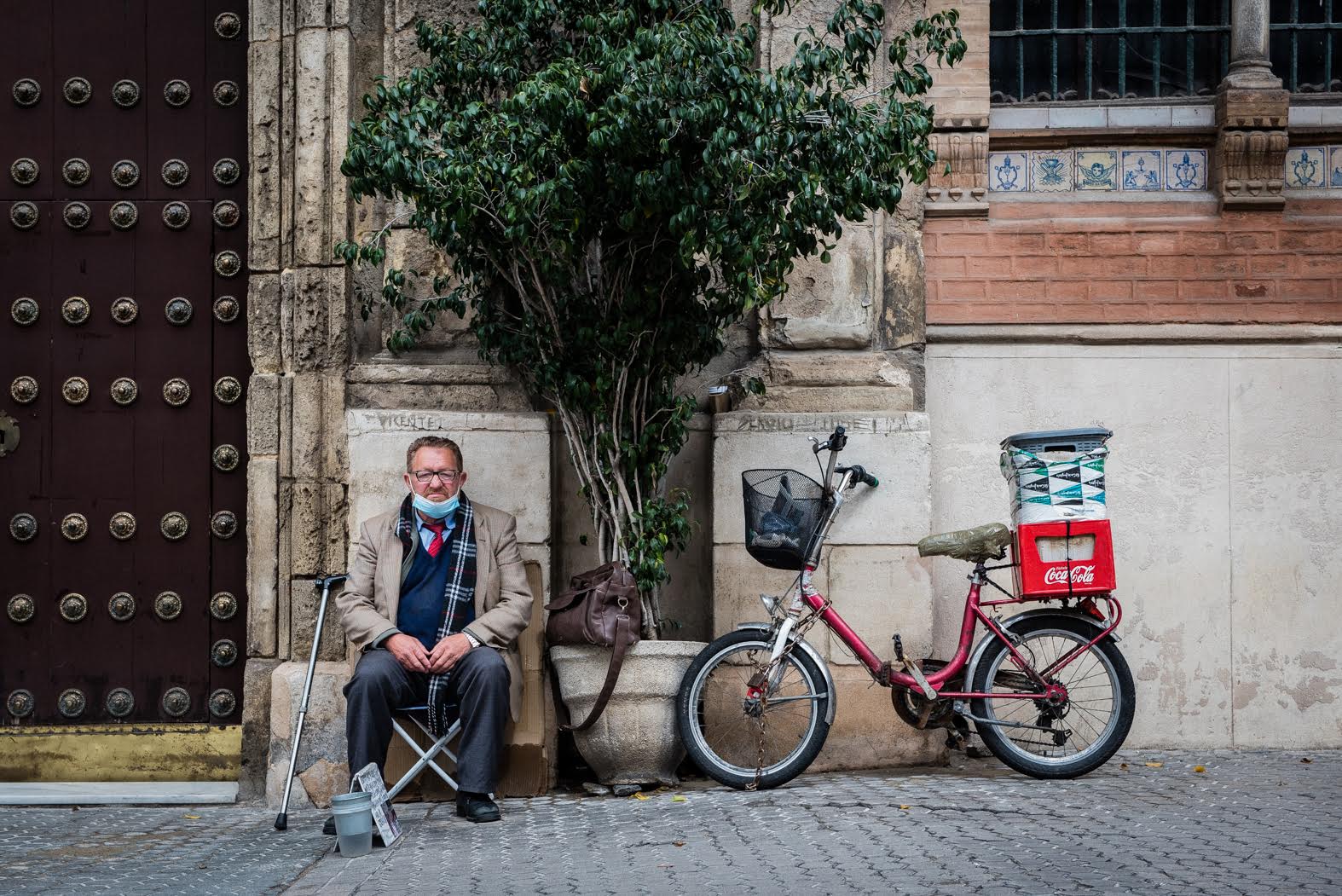 Mihail sentado junto a su bicicleta en la entrada de la Iglesia de San Pedro de Sevilla.