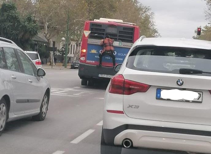 Un hombre se cuelga en la parte de atrás en un autobús de Sevilla. LI
