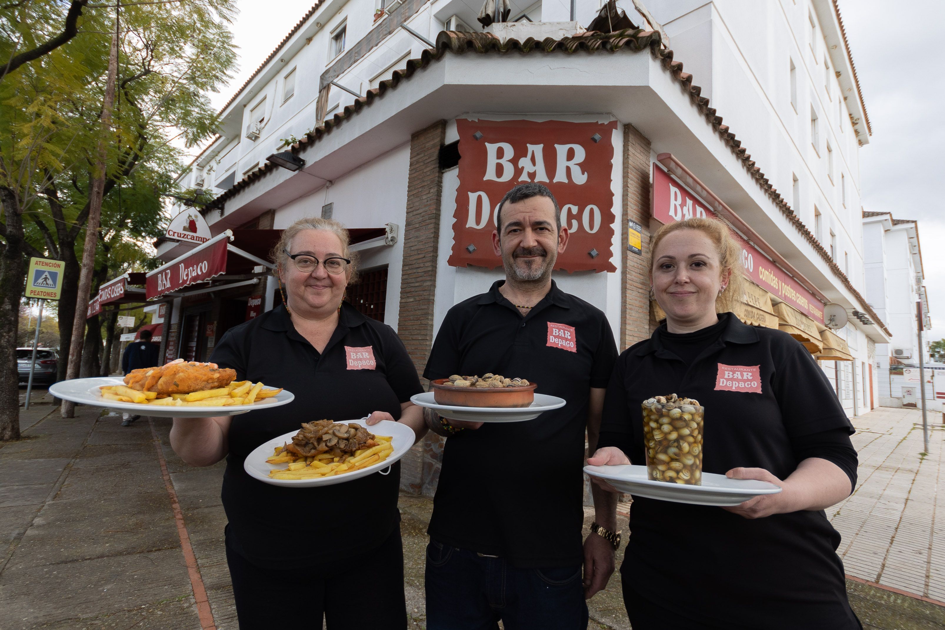 De izquierda a derecha, Rocío, Fernando y María del Mar, los dueños del Bar Depaco, con algunos de los platos típicos del bar, incluidos sus caracoles.