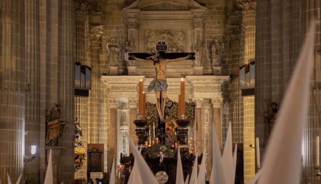 El paso del crucificado, ayer, dispuesto en su lugar una salida que no se produjo; por delante pasan nazarenos de La Sed.   CANDELA NUÑEZ