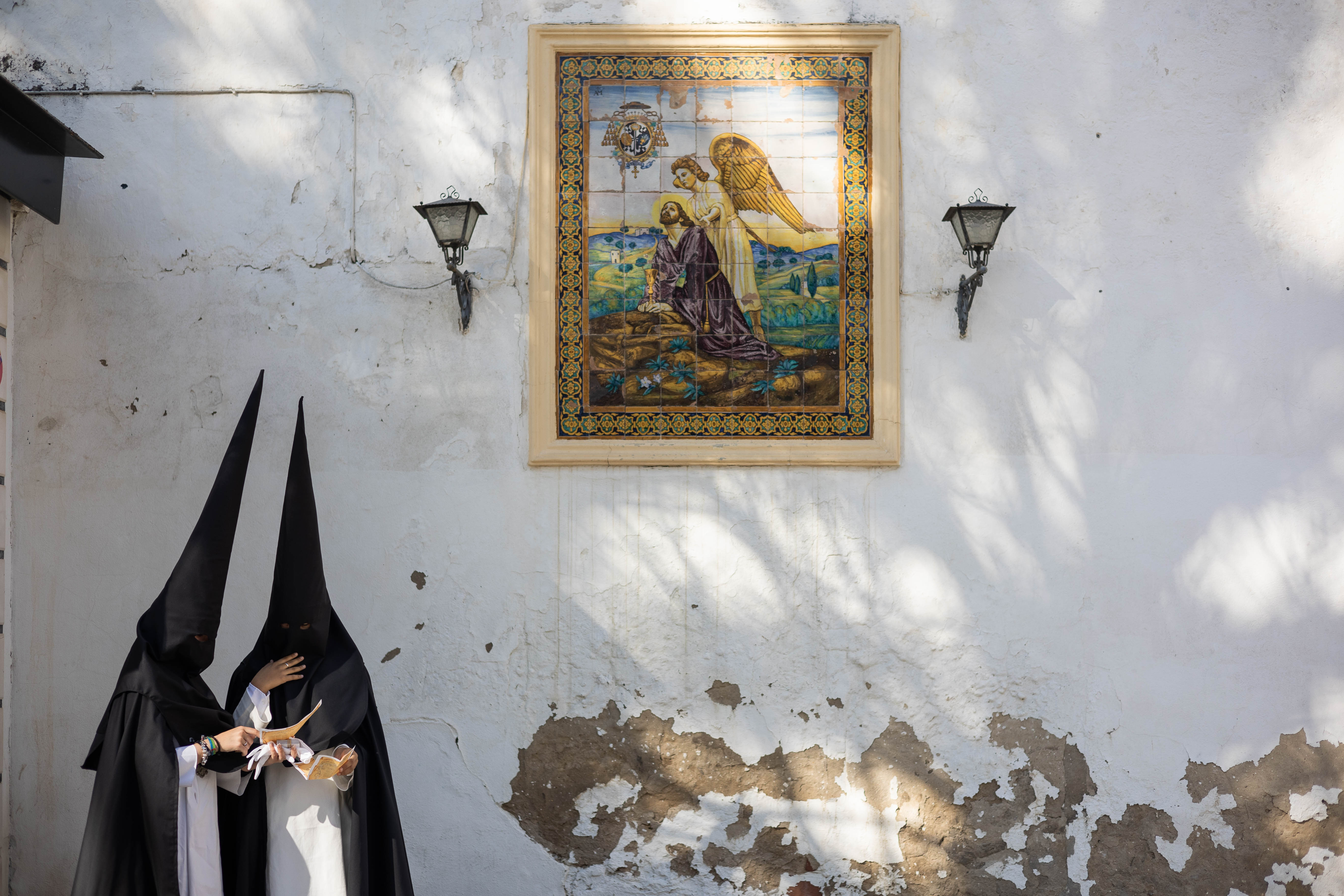 Dos nazarenos, al lado del azulejo de la Oración en el Huerto.