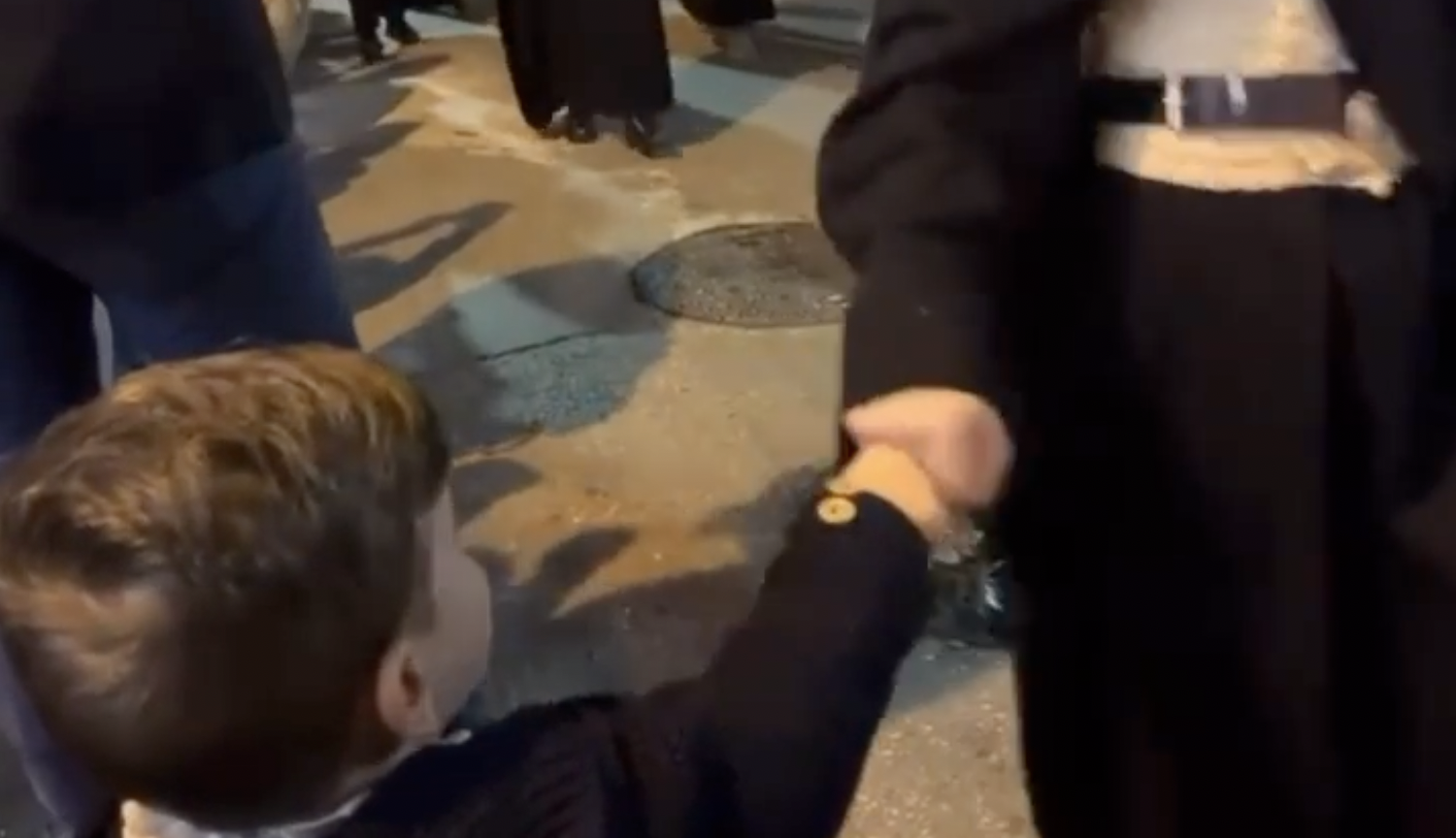 Un niño choca el puño de los nazarenos en la Semana Santa de Málaga.