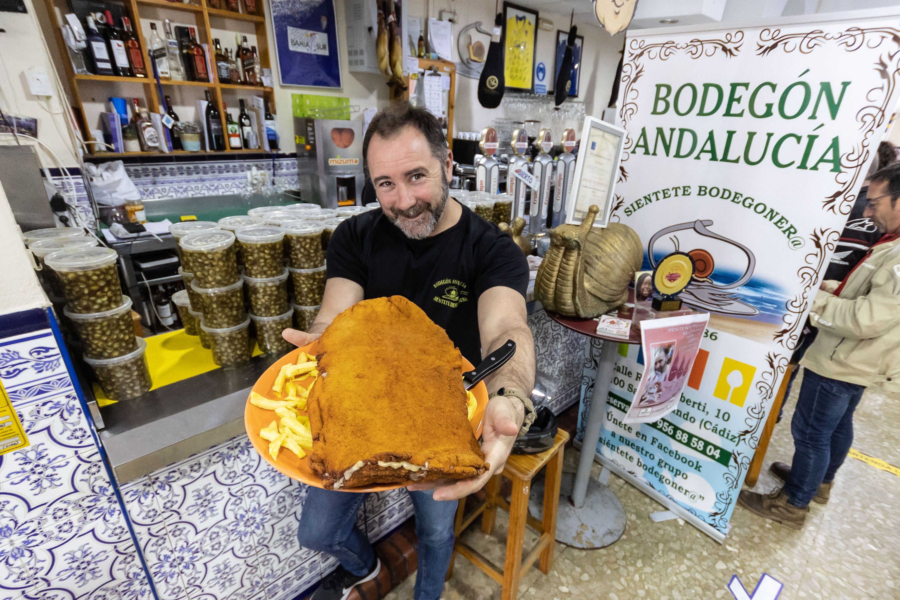 Alfonso García con un cachopo y las tarrinas de caracoles, las estrellas del Bodegón Andalucía en San Fernando.