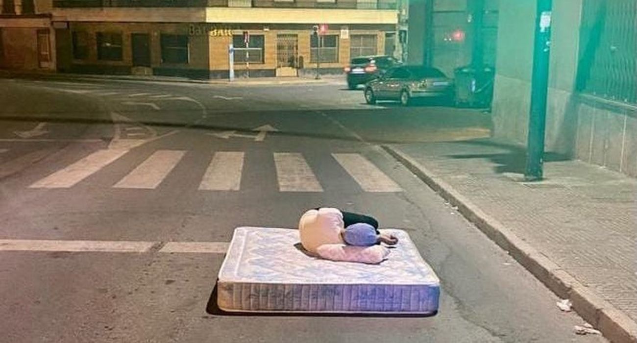 Un hombre duerme en plena carretera con colchón y almohada.