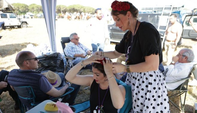 Coquetas: una rociera, cofrade de la Yedra, ayuda a otra a colocar la flor en el pelo.   ESTEBAN