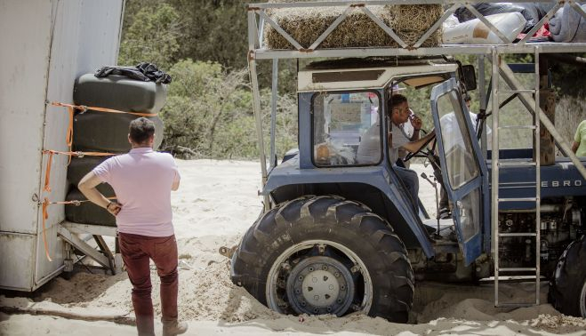 Un romero mira preocupado el estado del tractor y la carriola, atascados en la rodá. ESTEBAN