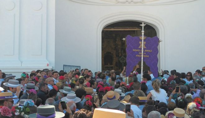 El simpecado en las puertas de la ermita, este mediodía, acompañado de centenares de rocieros
