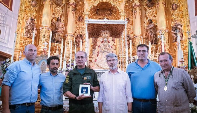 Los santeros y el homenajeado ante la Virgen del Rocío con la placa que la entregado la hermandad Matriz.     HERMANDAD MATRIZ