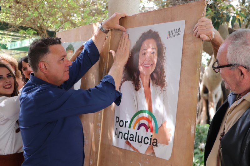 Juan Antonio Delgado, de Podemos, pegando un cartel de Por Andalucía con la imagen de Inma Nieto.