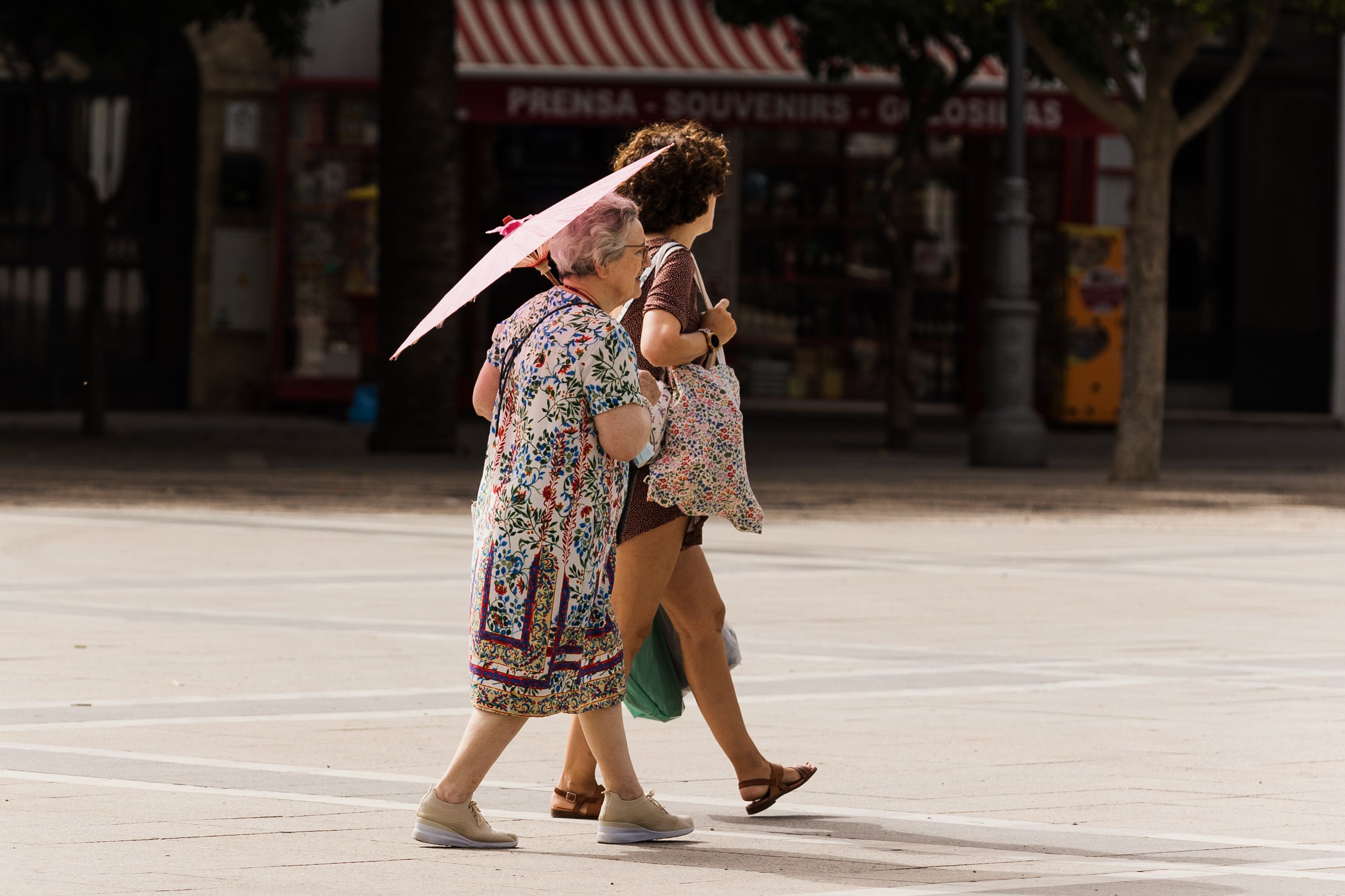 Dos mujeres pasean con una sombrilla para salvaguardarse de las altas temperaturas.  