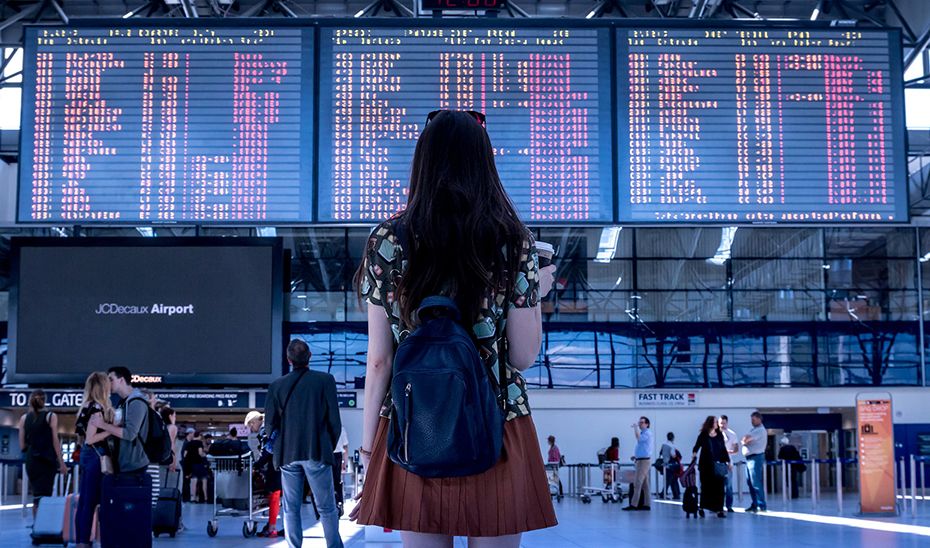 Una mujer observa las pantallas con los vuelos de un aeropuerto de Aena, que augura una buena recuperación con más asientos ofertados que en 2019.