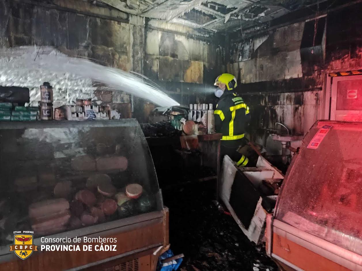 Un bombero en labores de extinción dentro de la carnicería de Los Barrios.