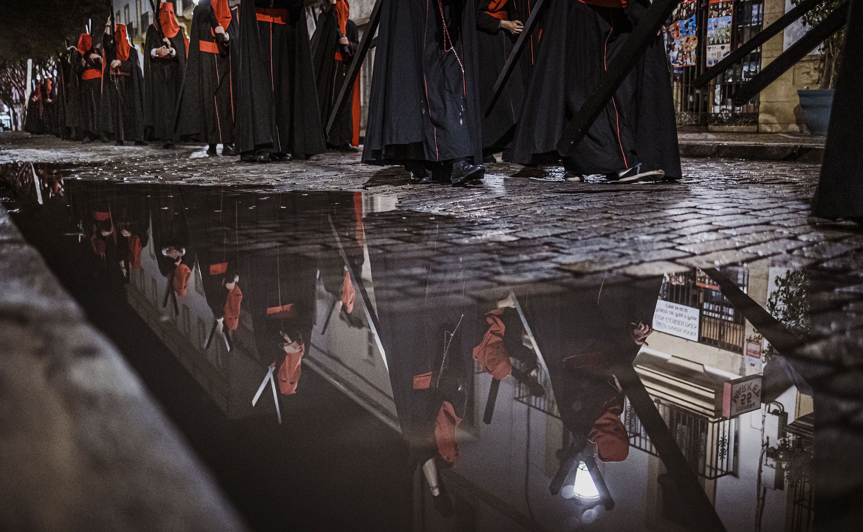 Nazarenos de los Judíos reflejados en un charco de agua en Porvera el pasado Martes Santo de lluvia.