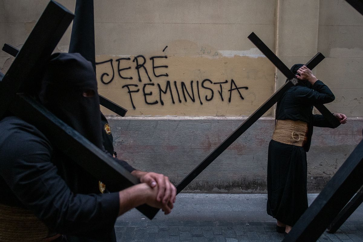 Penitentes de Las Angustias, cruces al hombro, ante una pintada en Jerez. FOTO: MANU GARCÍA.