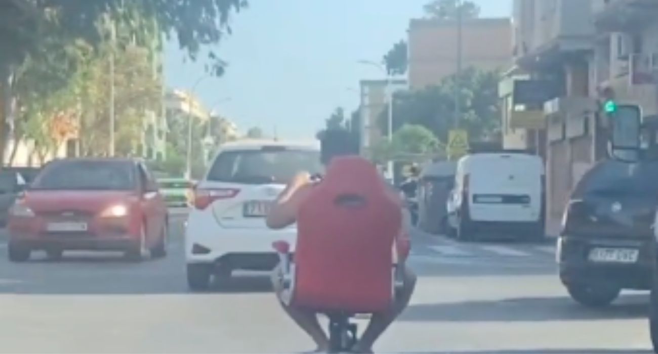 Un hombre circulando por Málaga en un patinete con una silla 'gaming'. La DGT exigirá un seguro obligatorio.
