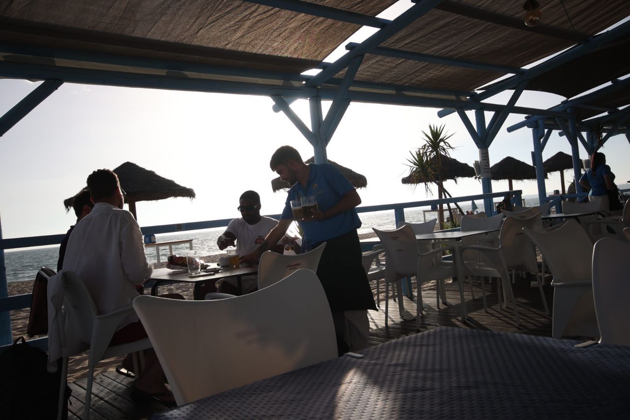 Un camarero atiende una mesa de un chiringuito en El Puerto.