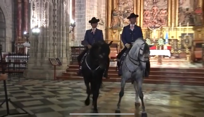  jinetes y sus monturas haciendo movimientos de doma ante el retablo del templo. 