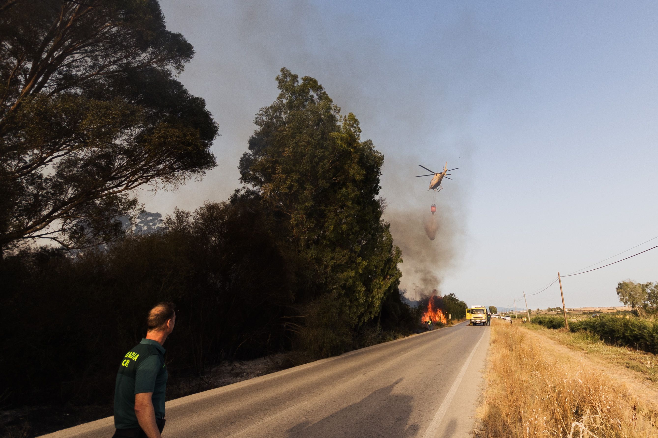 Un guardia civil observa al helicóptero que suelta agua sobre las llamas. 