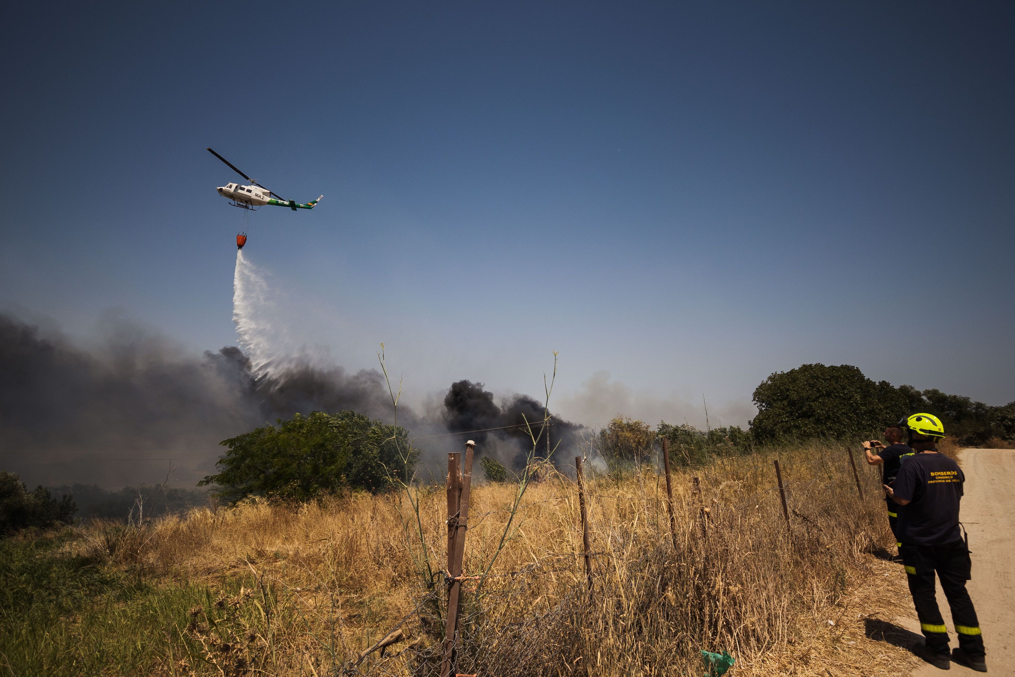 El helicóptero vierte agua ante la gran humareda.