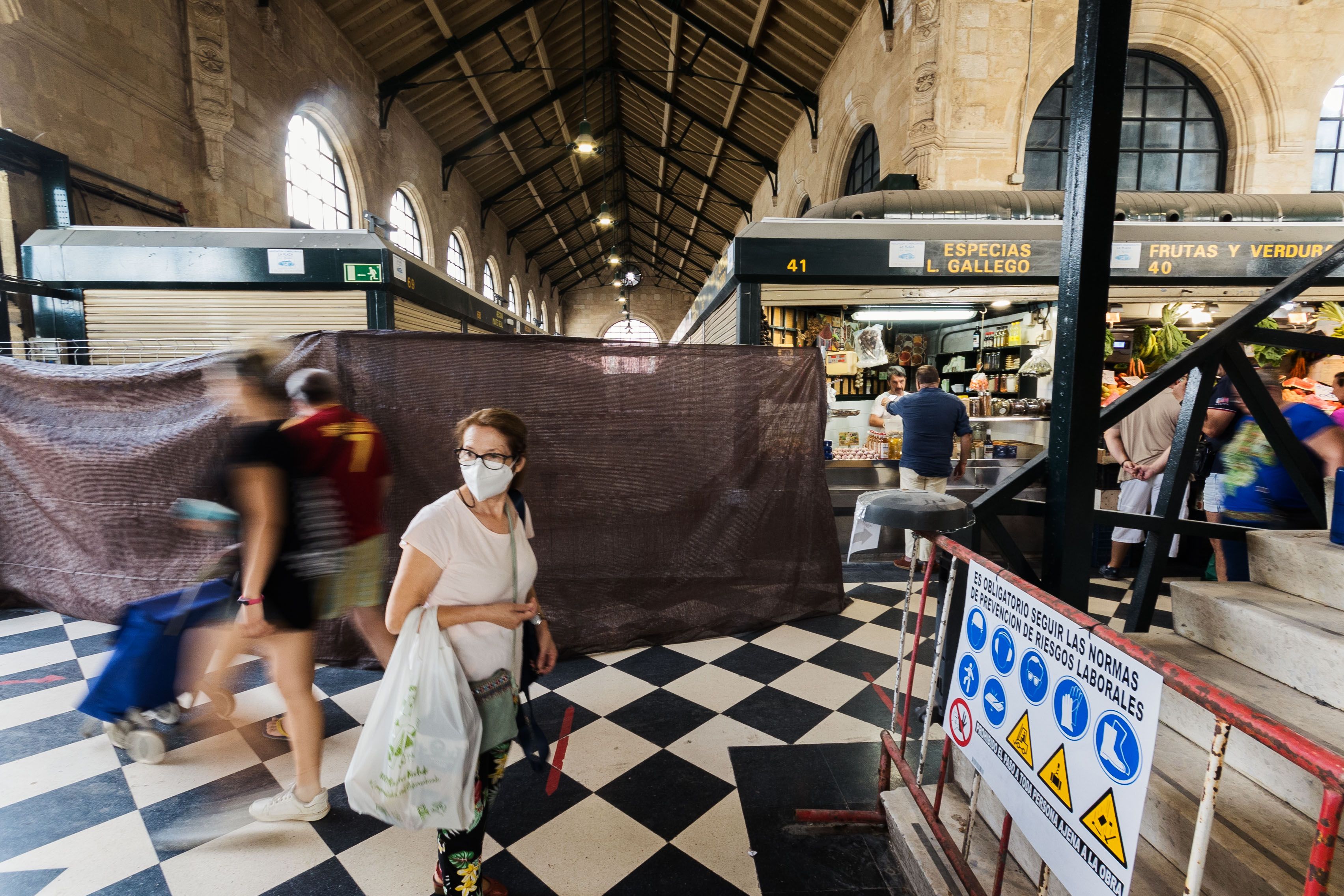 Una clienta pasa entre la zona vallada y los puestos abiertos.