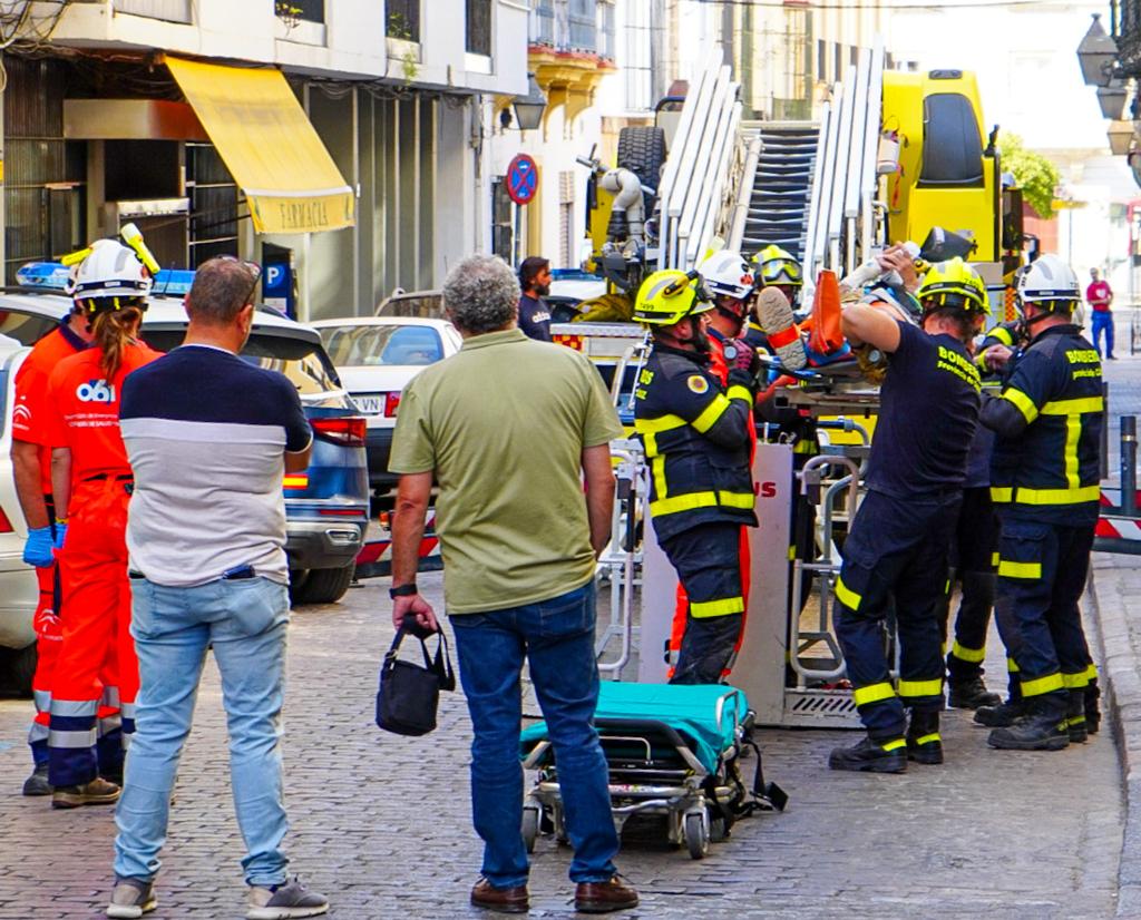 Imagen de los bomberos trasladando a la calle al operario accidentado en Jerez.