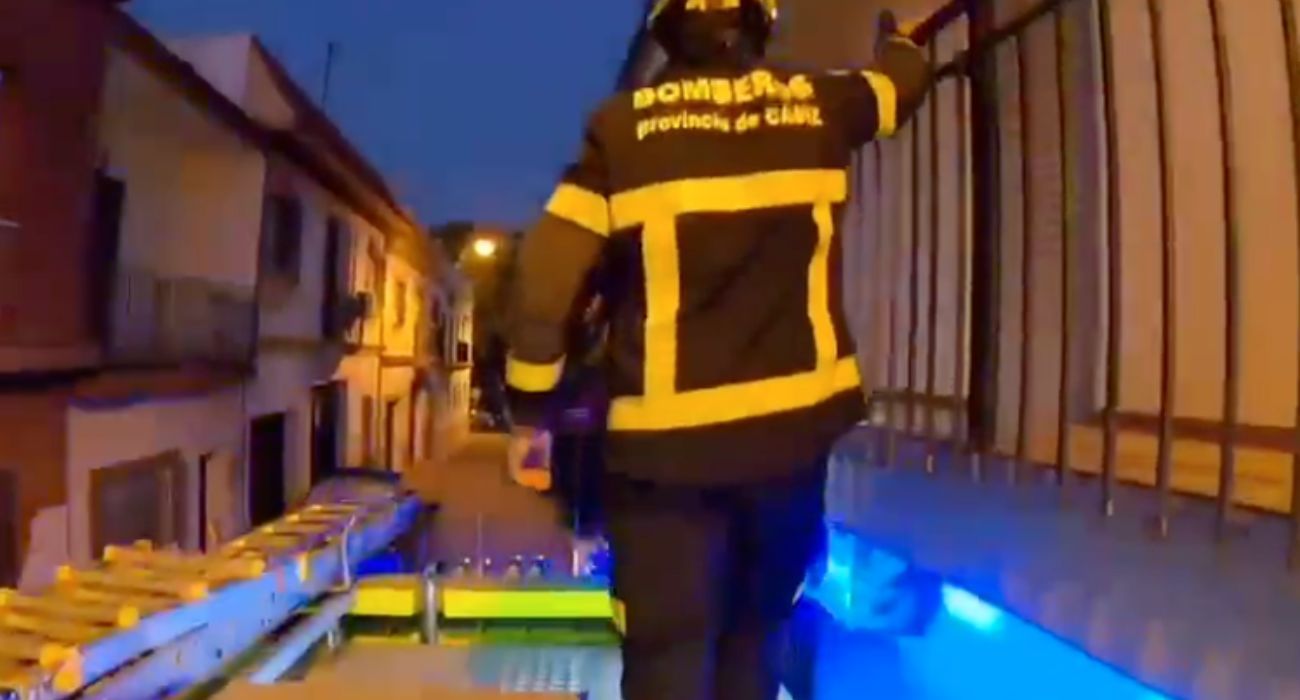 Un bombero, subido al techo del camión, para entrar por la ventana de la vivienda de la mujer accidentada.