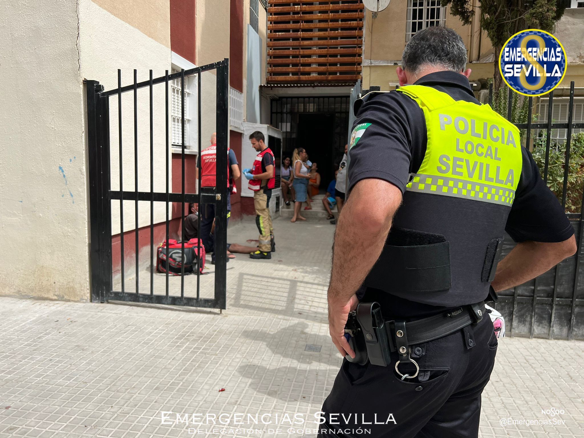 El herido, sentado en el suelo, tras sufrir un golpe en la cabeza en Sevilla mientras iba caminando.