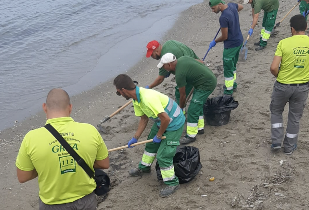 Prohibido el baño: acordonada la playa de Poniente en La Línea por el vertido del OS35. En la imagen, operarios este viernes limpiando la playa.