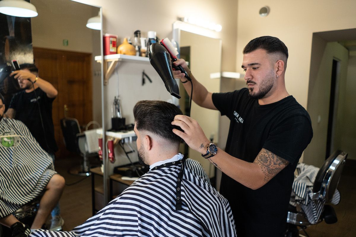 Ismael Ayala, pelando a un cliente, una de las peluquerías que resiste la crisis.