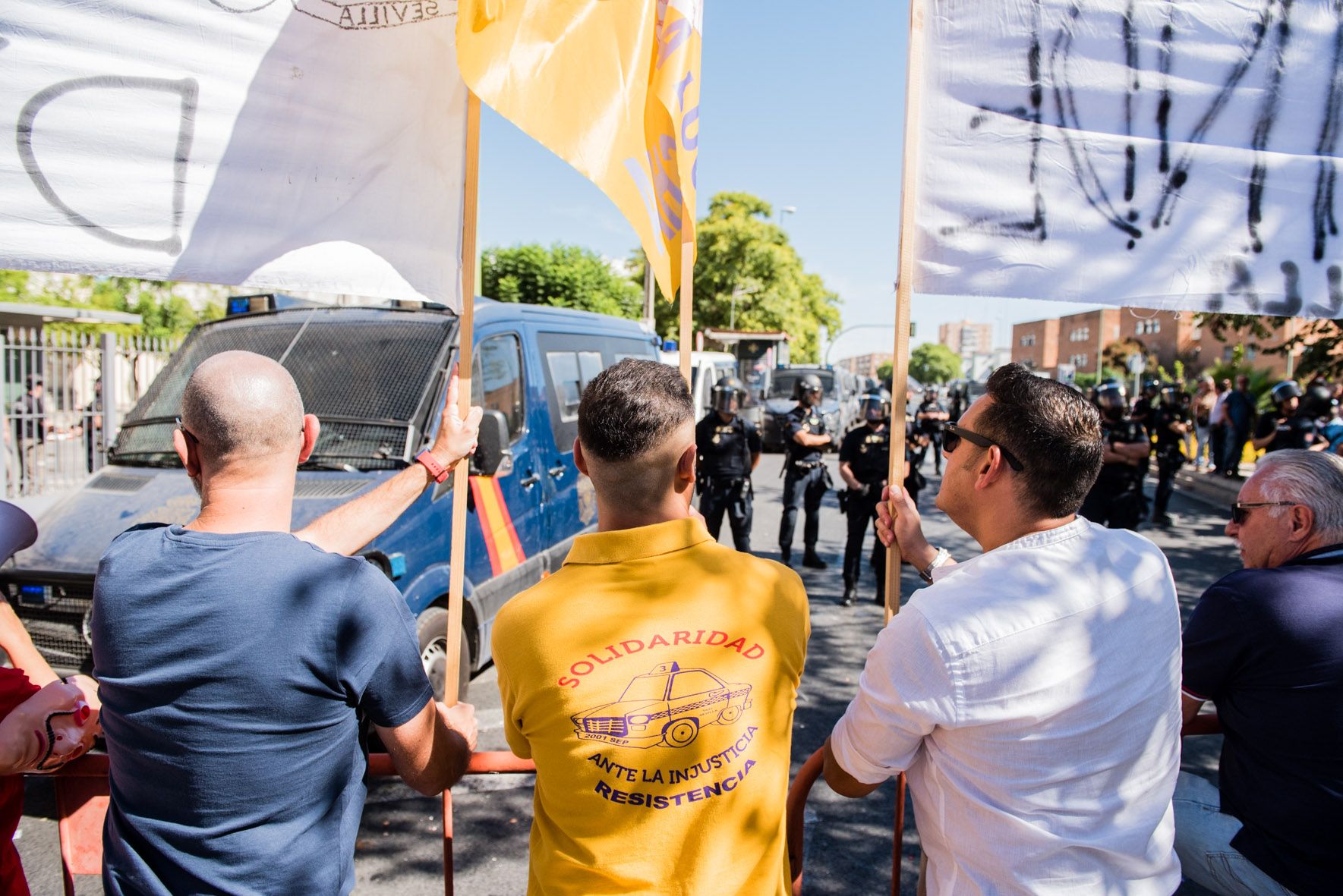 Taxistas manifestándose en Sevilla, con agentes de Policía Nacional delante.