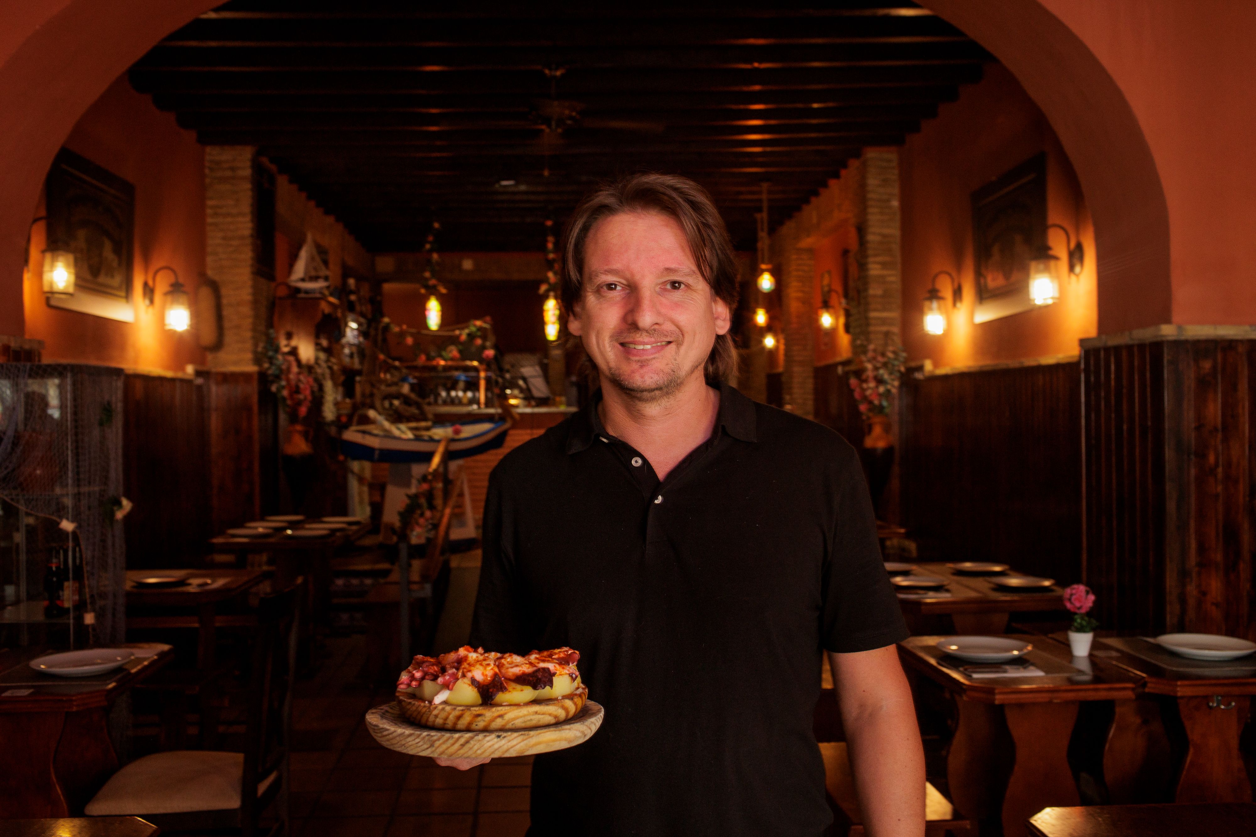 Daniel con el plato de pulpo en el interior del local.