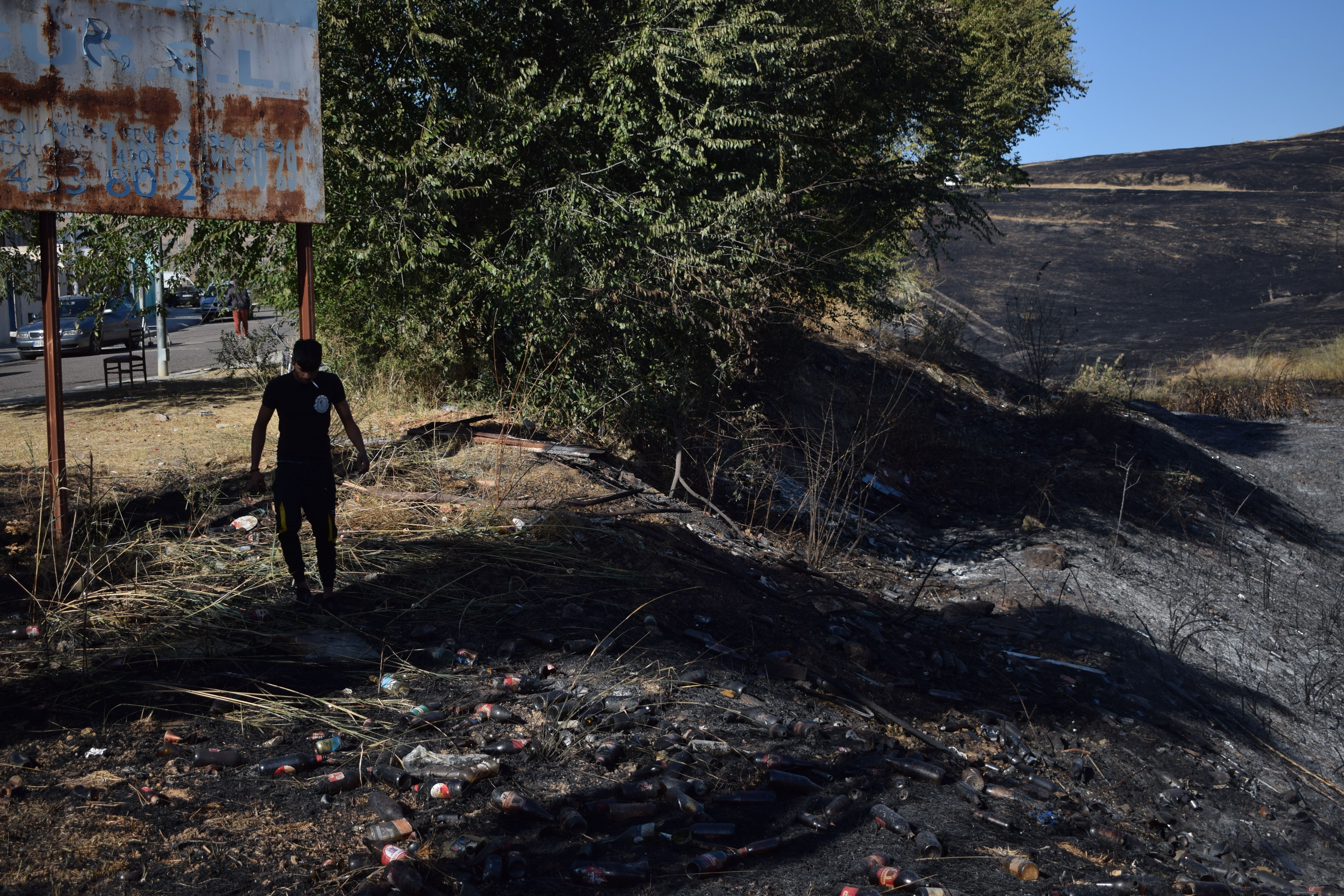 Uno de los vecinos desalojados por el incendio en Camas recoge basura.