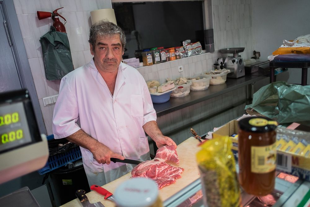 Eulogio Guerrero trabajando en su carnicería un día después de ser asaltado y acuchillado en su propio negocio. FOTO: MANU GARCÍA. 