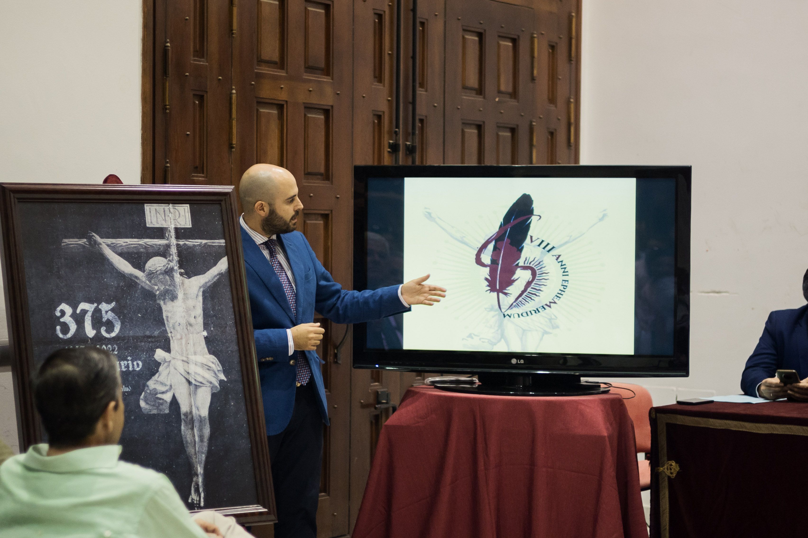 El oficial de la hermandad, Miguel Merino, mostrando el logo en el acto.     CANDELA NUÑEZ