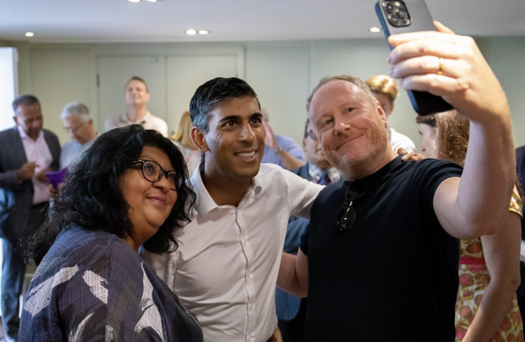 El multimillonario de origen hindú Rishi Sunak se convertirá en primer ministro en Reino Unido. En la imagen de su cuenta de Twitter, haciéndose un selfie con dos simpatizantes.