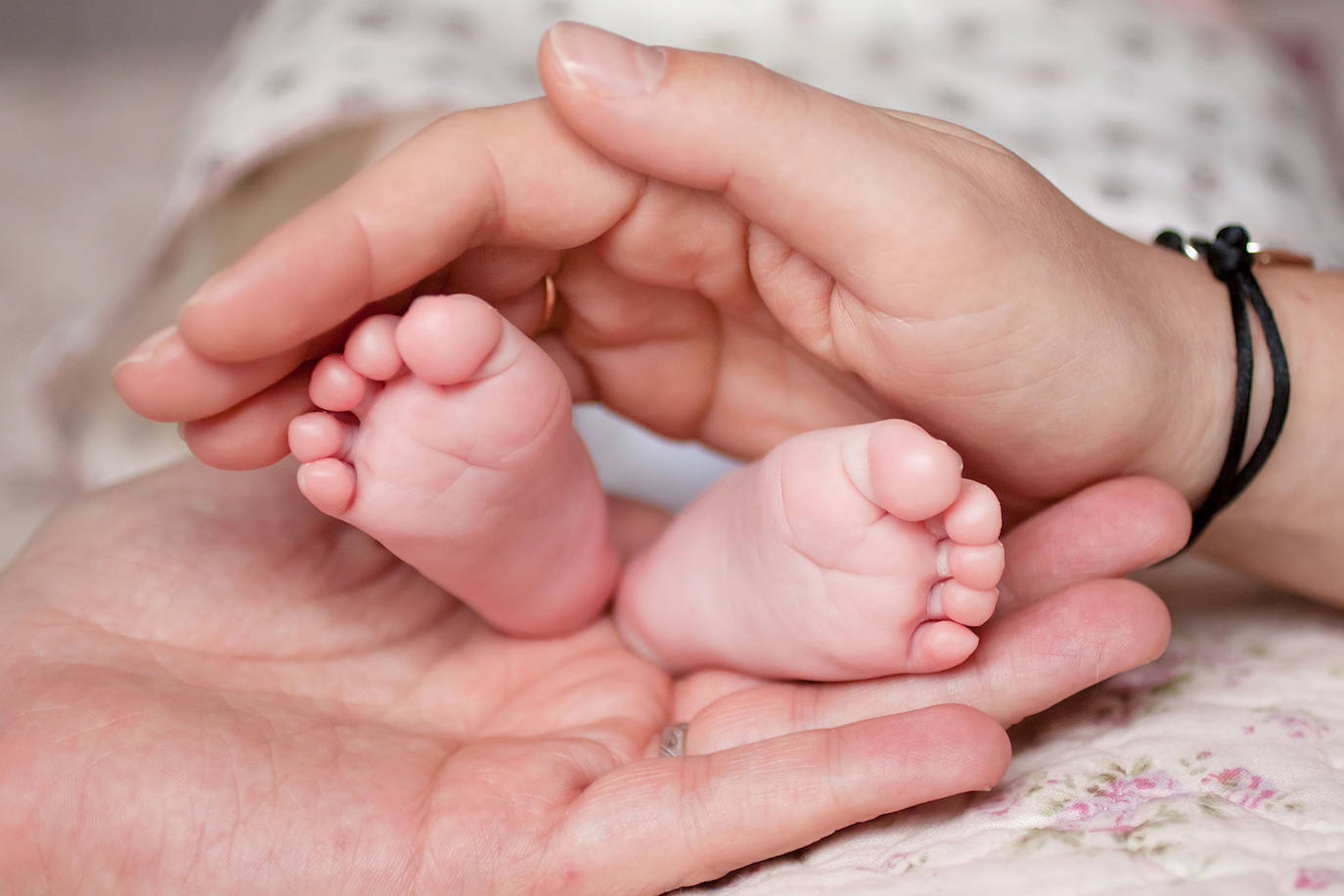 Los pies de un bebé entre las manos de la madre.