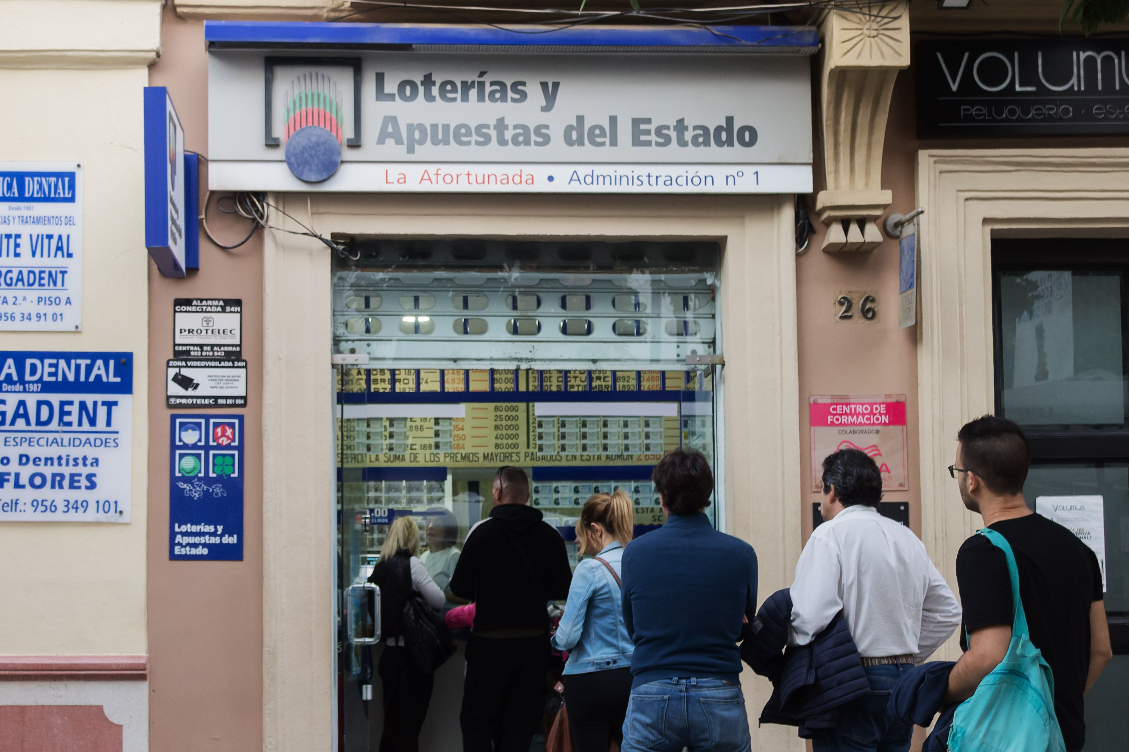 Gente haciendo cola en una administración de Loterías. 