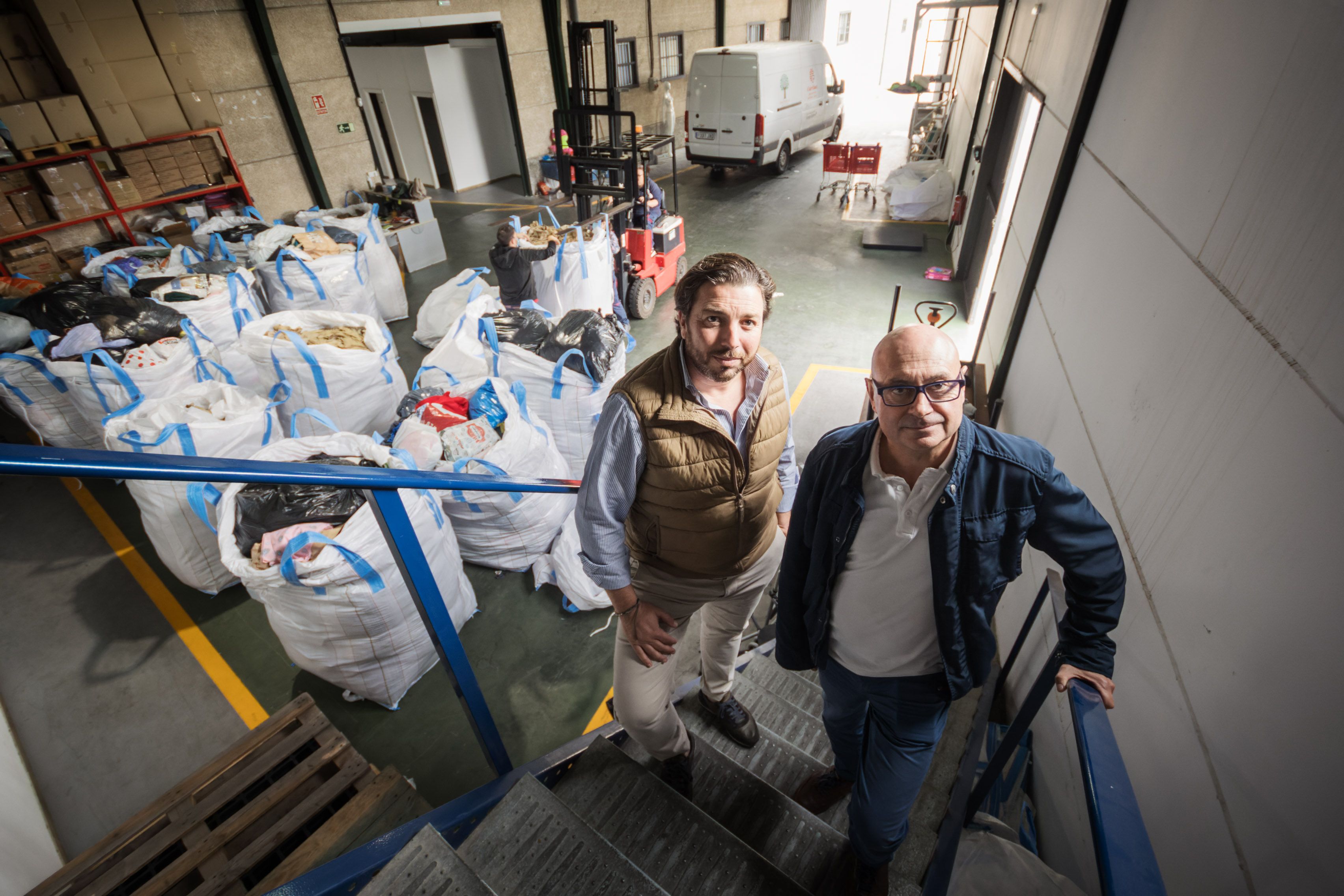 Juan Antonio García y José Manuel Jiménez, responsables de Casa Común y de Economía Social de Cáritas, delante de las sacas con la ropa recogida.