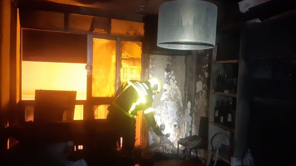 Un bombero junto al aire acondicionado que sale ardiendo.