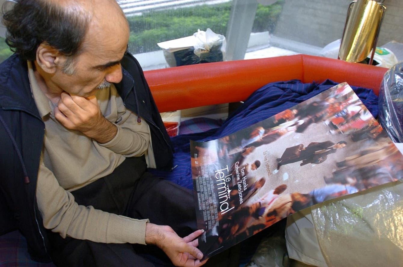 Muere en Paris el iraní que inspiró la película ‘La terminal’. Mehran Karimi Naseri viendo una revista sobre la película 'La terminal'.