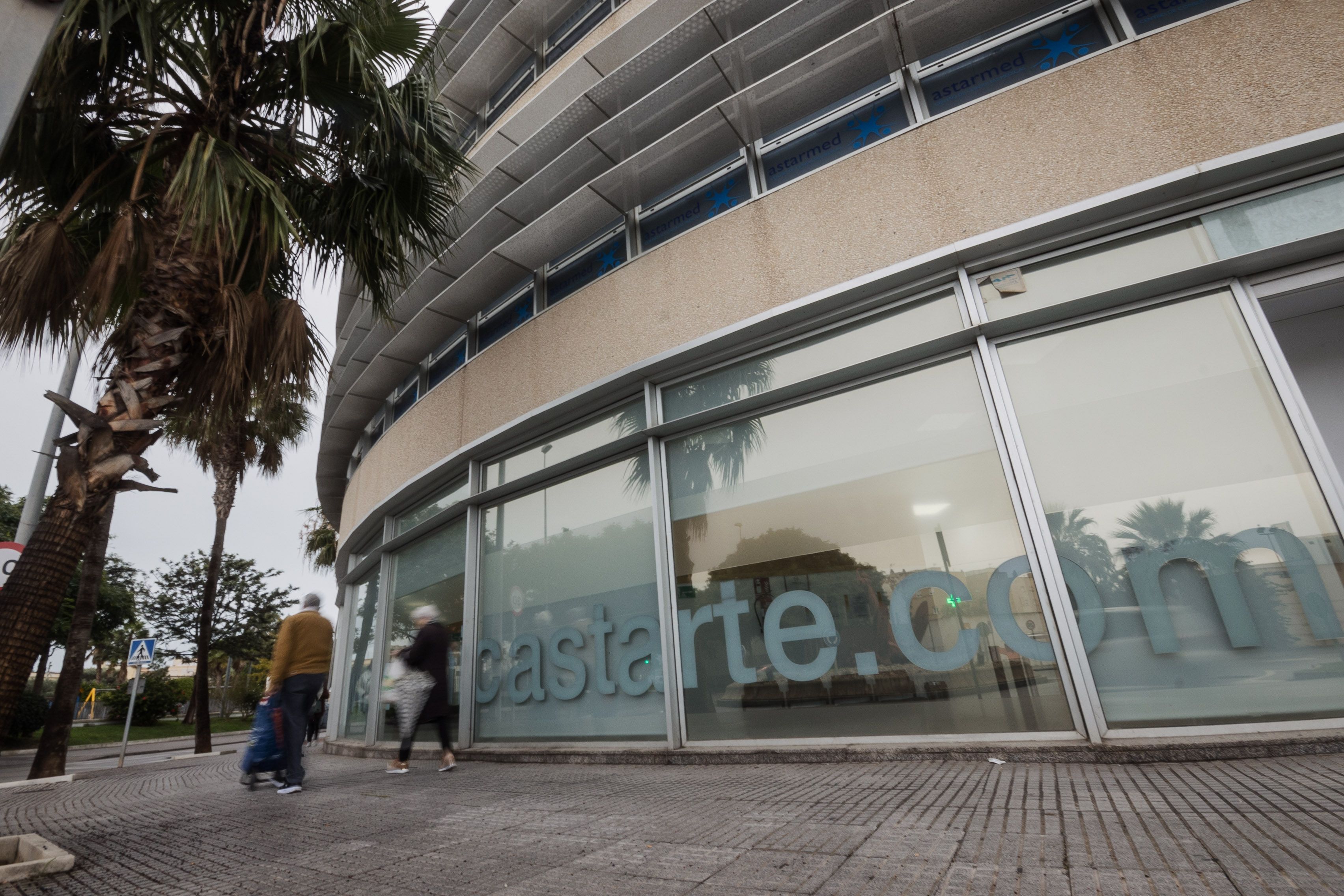 Dos personas pasan por delante de la Clínica Astarté de Cádiz.