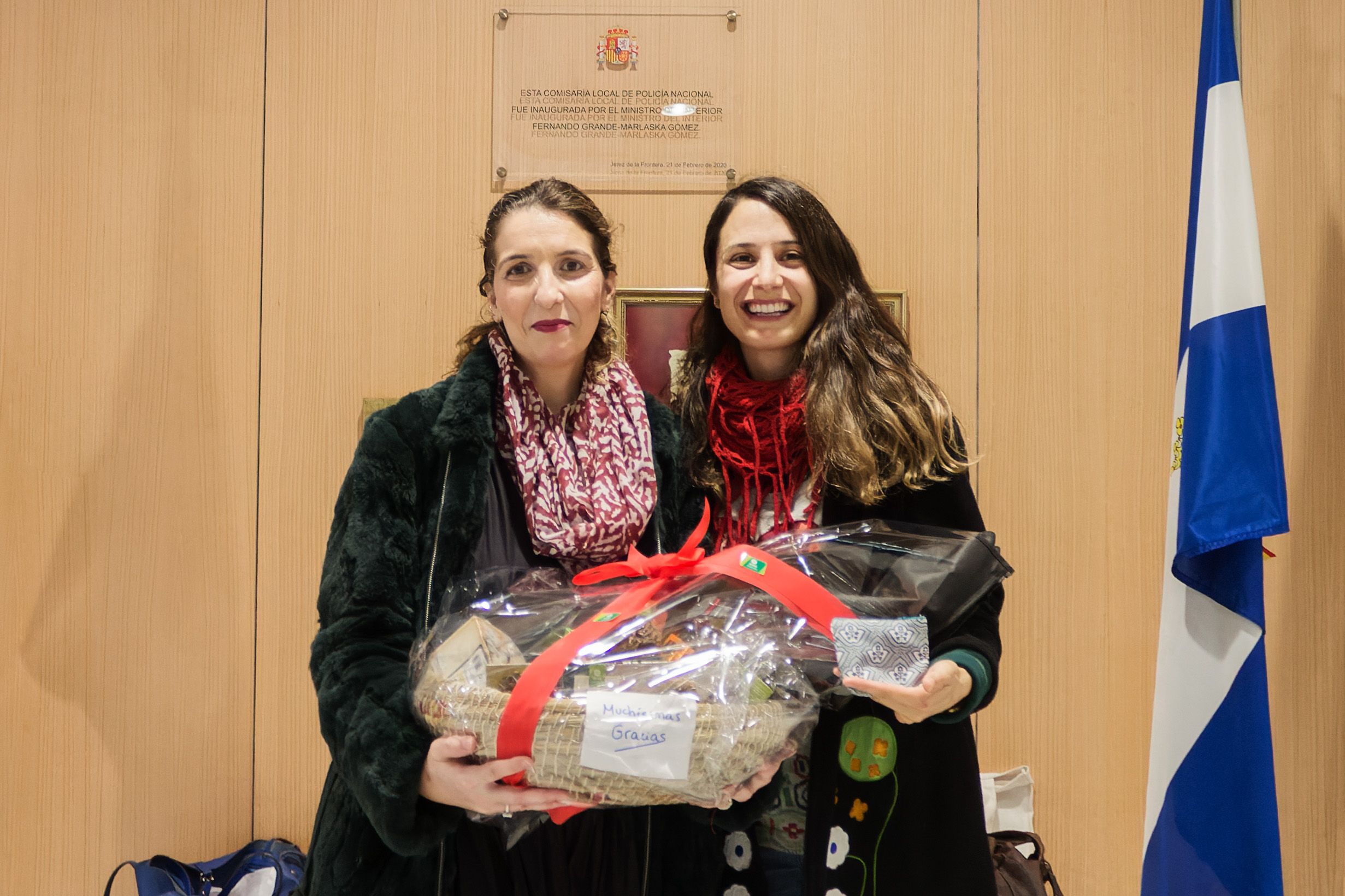 María Cruz, en la derecha, entregando a María Gracia, en la izquierda, la cesta navideña en la sede de la Comisaría jerezana. 