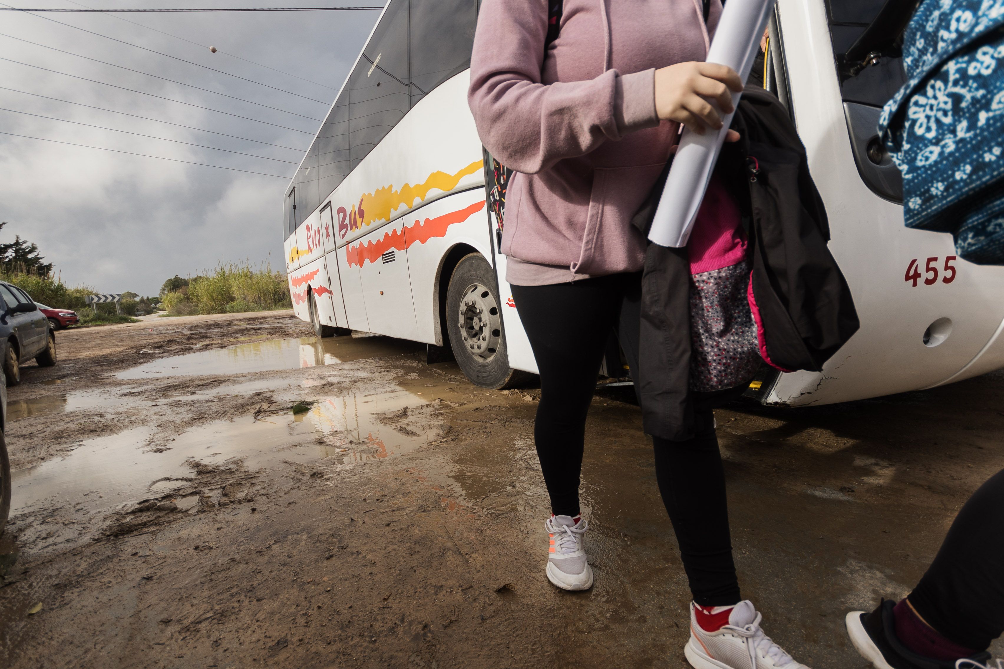 Una de las niñas esquiva los charcos al bajar del autobús.