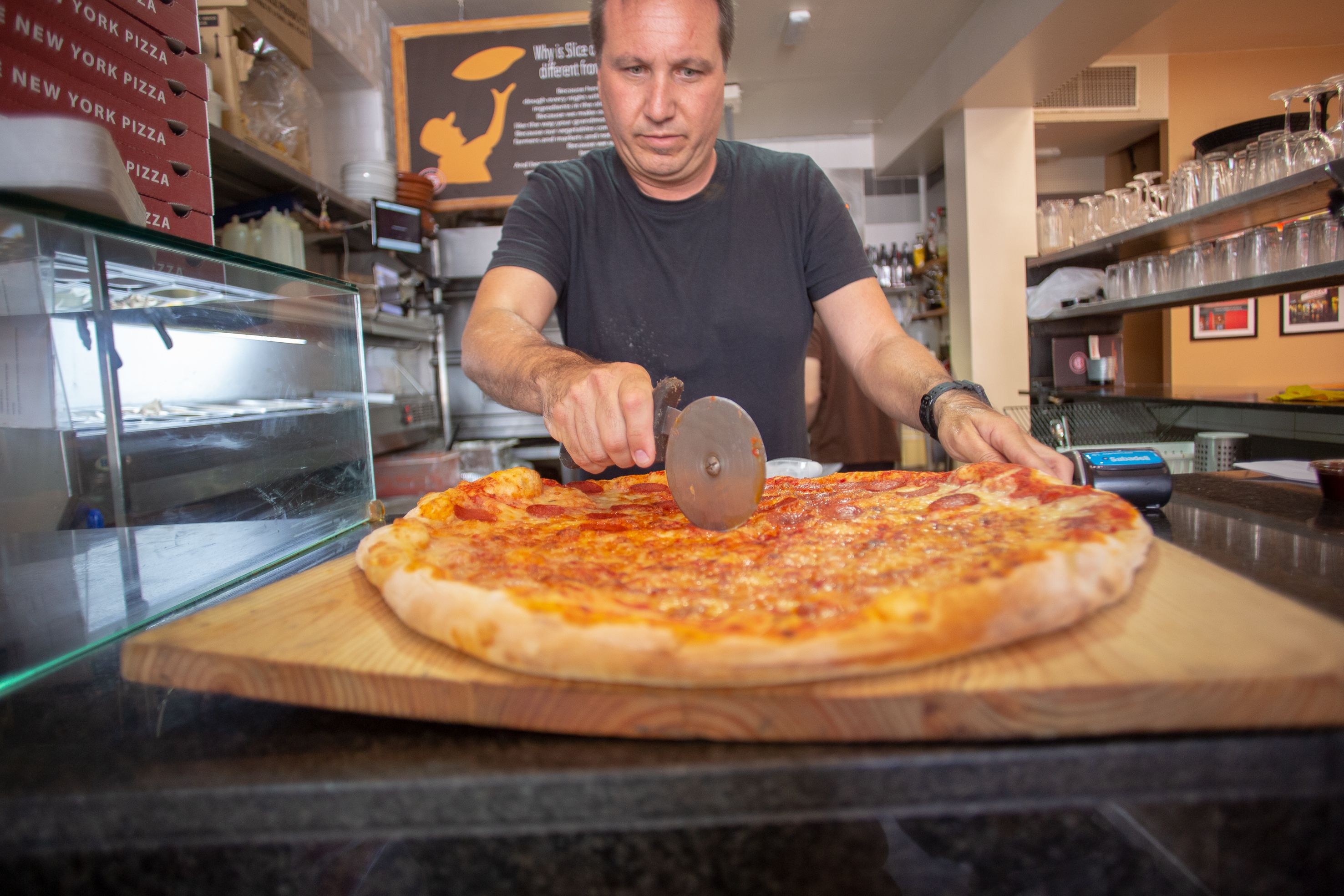 James Bem corta una porción de su pizza, en su local de Slice of New York en Rota. JUAN CARLOS TORO