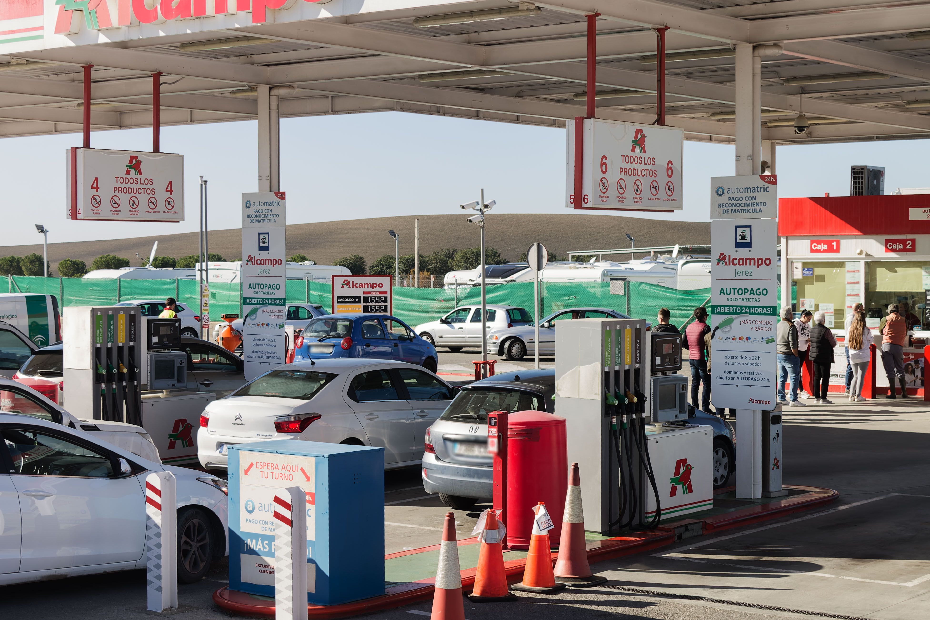 Coches repostando en una gasolinera, donde el diésel y la gasolina están en mínimos anuales.
