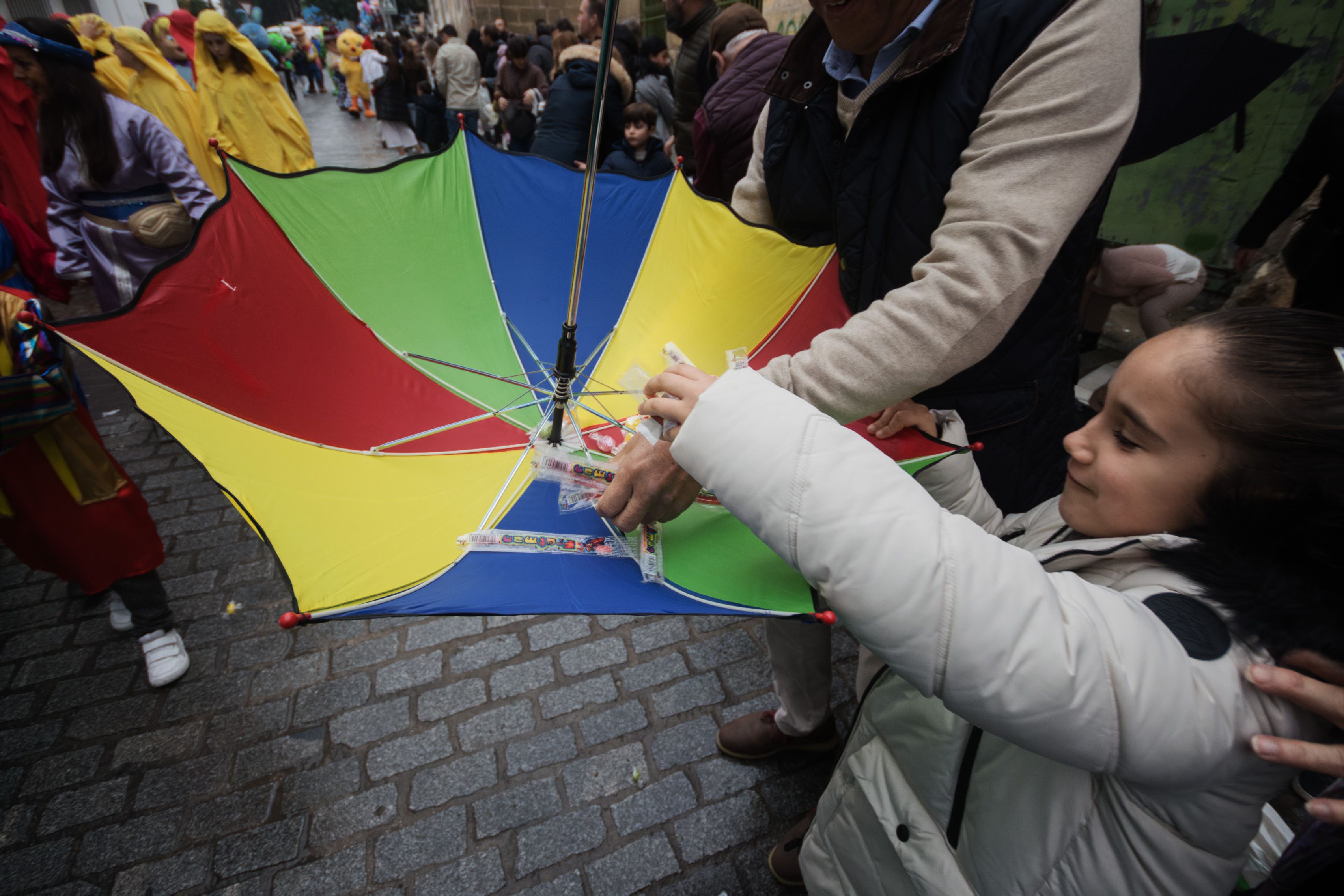 Satisfacción en una pequeña recogiendo los caramelos recogidos en su paraguas puesto del revés.     CANDELA NÚÑEZ