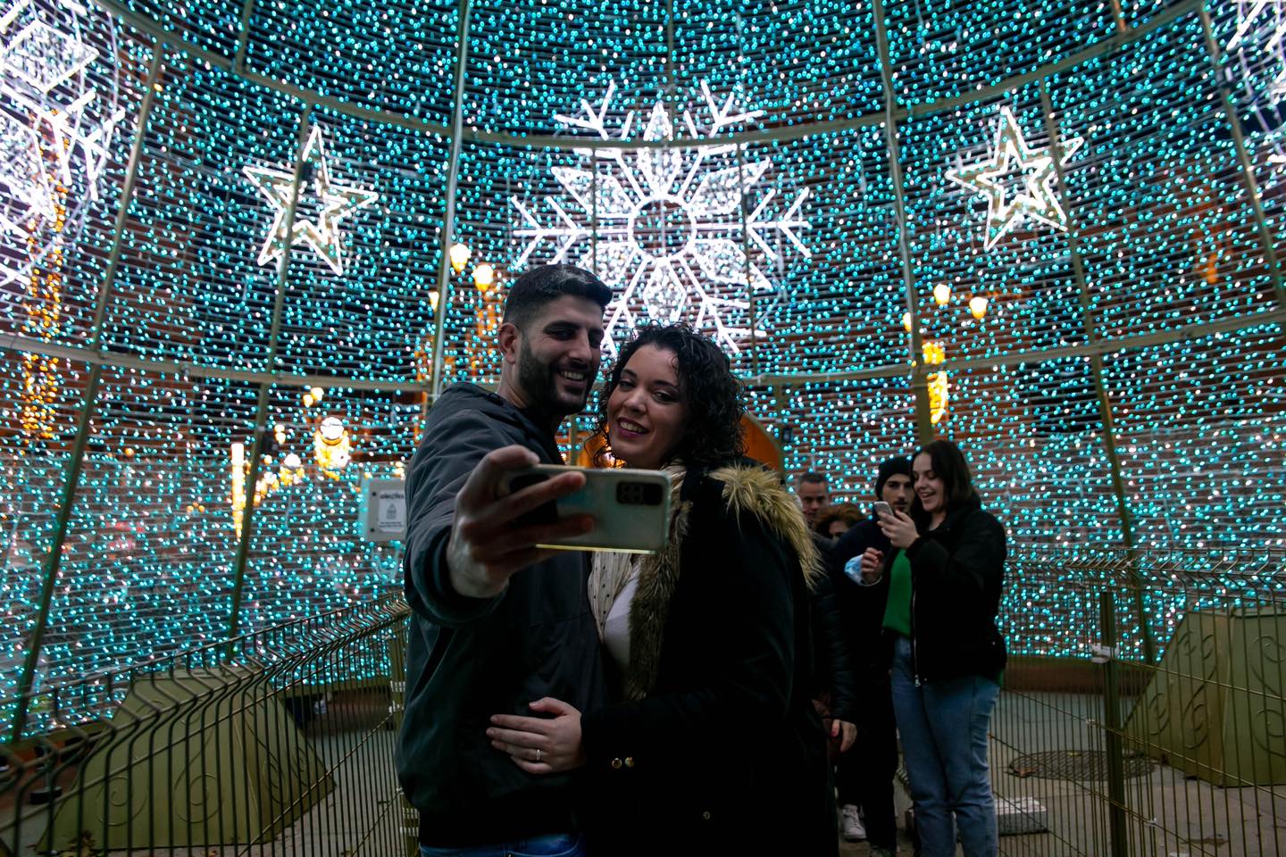 Una pareja se hace una foto en medio de decoración de Navidad.