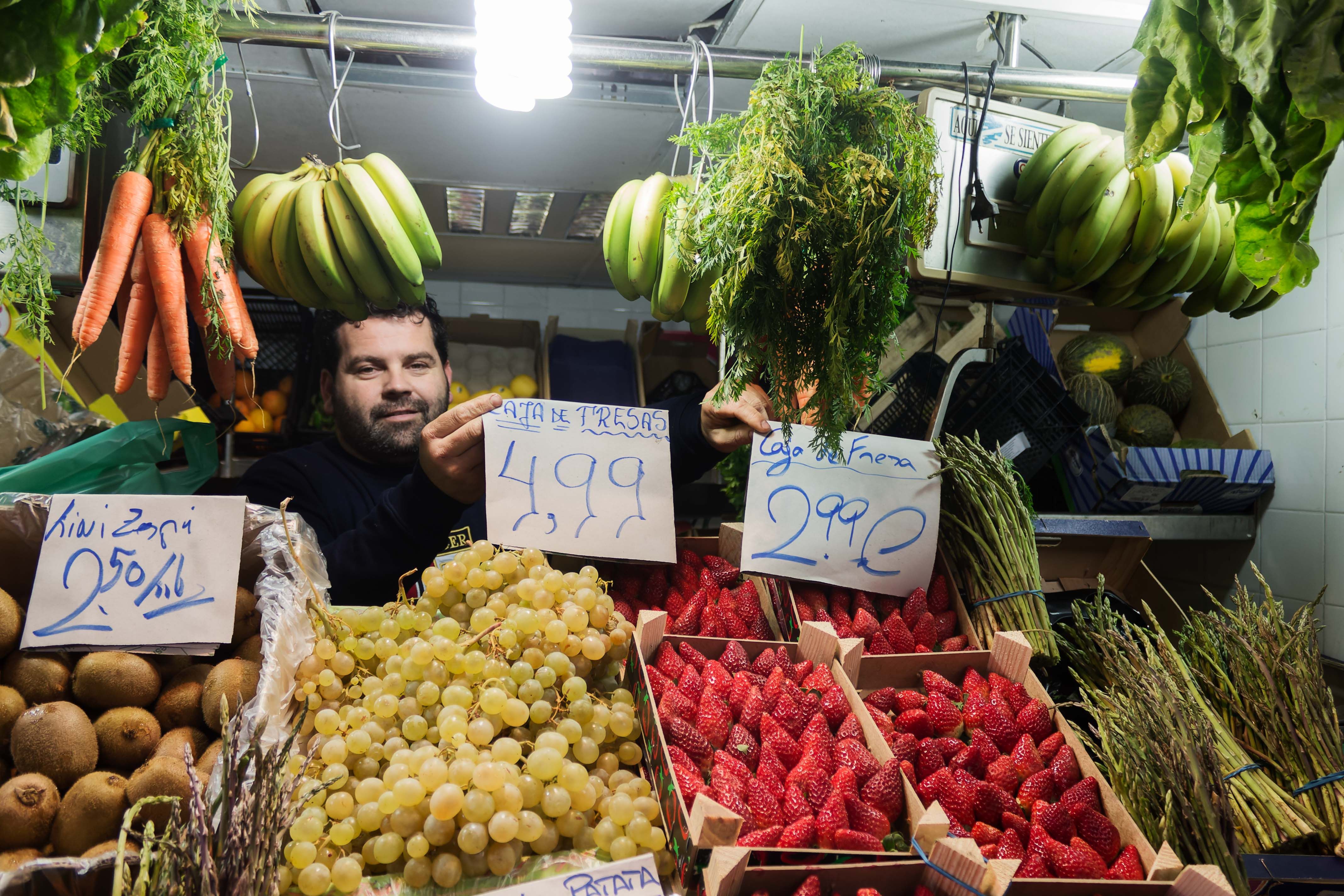 Javi, en su puesto del Mercado, con el antiguo y el nuevo cartel que marca el precio de las fresas.