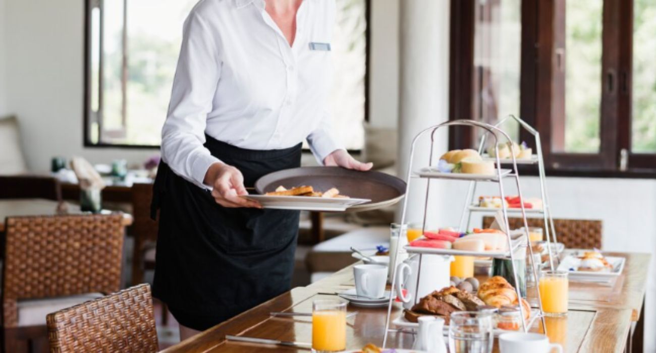 Una camarera, recogiendo un desayuno en un hotel.