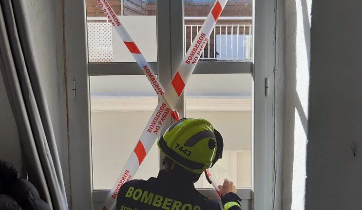 Un bombero precintando la ventana desde la que cayó el estudiante.